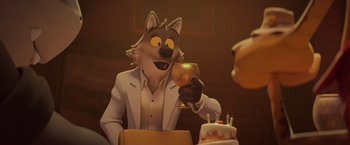 Movie still from “The Bad Guys” (2022), directed by Pierre Perifel – A man sitting in front of a cake with a glass in his hand; Medium shot, Over the shoulder angle