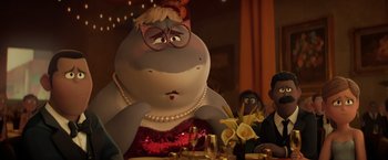 Movie still from “The Bad Guys” (2022), directed by Pierre Perifel – A woman sitting at a dinner table with a glass of wine; Medium shot, Over the shoulder angle