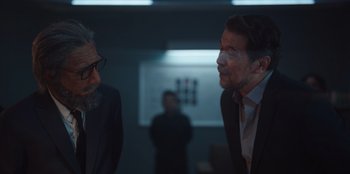 Movie still from “The Big 4” (2022), directed by Timo Tjahjanto – Two men in suits talking to each other in a room; Medium shot, Over the shoulder angle