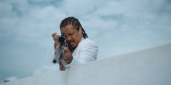 Movie still from “The Big 4” (2022), directed by Timo Tjahjanto – A man in a white jacket is taking a picture with a camera; Close Up shot, Low angle
