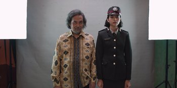 Movie still from “The Big 4” (2022), directed by Timo Tjahjanto – A man standing next to a woman wearing a uniform; Medium shot, Low angle