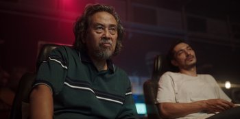 Movie still from “The Big 4” (2022), directed by Timo Tjahjanto – An older man sitting next to a woman in a chair; Medium shot, Low angle