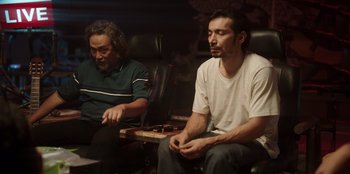 Movie still from “The Big 4” (2022), directed by Timo Tjahjanto – Two men sitting in a chair and one of the men is holding a game controller; Medium shot, Low angle