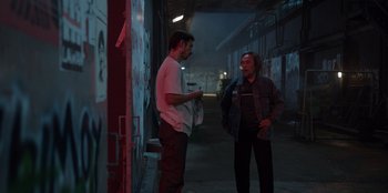 Movie still from “The Big 4” (2022), directed by Timo Tjahjanto – Two men standing next to each other on a street; Medium shot, Over the shoulder angle