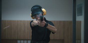 Movie still from “The Big 4” (2022), directed by Timo Tjahjanto – A man wearing ear muffs and holding a gun; Close Up shot, Over the shoulder angle