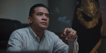 Movie still from “The Big 4” (2022), directed by Timo Tjahjanto – A man sitting down while holding a cigarette in his hand; Close Up shot, Low angle
