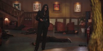 Movie still from “The Big 4” (2022), directed by Timo Tjahjanto – A woman standing in a room next to a man laying on the ground; Wide shot, High angle