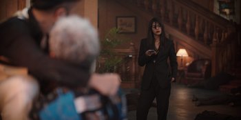 Movie still from “The Big 4” (2022), directed by Timo Tjahjanto – A woman in a black suit is looking at her cell phone; Wide shot, Over the shoulder angle
