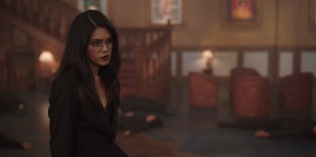 Movie still from “The Big 4” (2022), directed by Timo Tjahjanto – A woman in a black dress and glasses; Medium shot, Over the shoulder angle