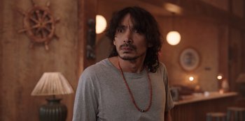 Movie still from “The Big 4” (2022), directed by Timo Tjahjanto – A man with long black hair wearing a necklace; Close Up shot, Over the shoulder angle