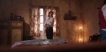 Movie still from “The Big 4” (2022), directed by Timo Tjahjanto – A woman standing on a bed in front of a window; Wide shot, Low angle
