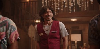 Movie still from “The Big 4” (2022), directed by Timo Tjahjanto – A man in a red vest smiling for the camera; Medium shot, Over the shoulder angle