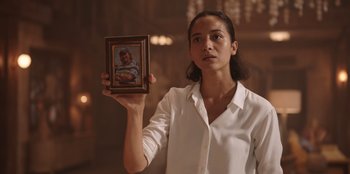 Movie still from “The Big 4” (2022), directed by Timo Tjahjanto – A woman holding a picture of a man in a picture frame; Close Up shot, Low angle