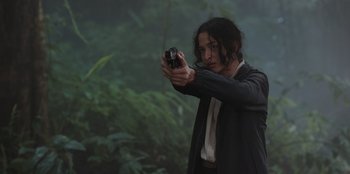 Movie still from “The Big 4” (2022), directed by Timo Tjahjanto – A woman is holding a gun in the woods; Medium shot, Low angle