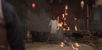 Movie still from “The Big 4” (2022), directed by Timo Tjahjanto – A man standing on steps in front of a burning house; Wide shot, Low angle