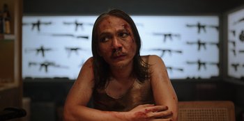 Movie still from “The Big 4” (2022), directed by Timo Tjahjanto – A man with a bruised face sitting in front of a window; Close Up shot, Low angle