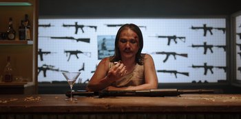 Movie still from “The Big 4” (2022), directed by Timo Tjahjanto – A woman sitting at a counter with a gun in front of her face; Medium shot, High angle