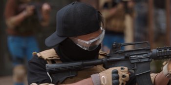 Movie still from “The Big 4” (2022), directed by Timo Tjahjanto – A man wearing a black hat and holding a rifle; Close Up shot, Over the shoulder angle