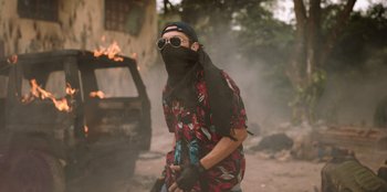 Movie still from “The Big 4” (2022), directed by Timo Tjahjanto – A man wearing sunglasses and holding a scarf around his neck; Medium shot, Low angle