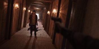 Movie still from “The Big 4” (2022), directed by Timo Tjahjanto – A person holding a gun while standing in a hallway; Wide shot, Over the shoulder angle