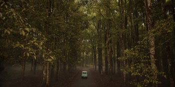 Movie still from “The Big 4” (2022), directed by Timo Tjahjanto – A car driving down a dirt road in the woods; Extreme Wide shot, High angle