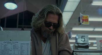 Movie still from “The Big Lebowski” (1998), directed by Ethan Coen – A man sitting at a desk in front of a computer; Medium shot, Low angle