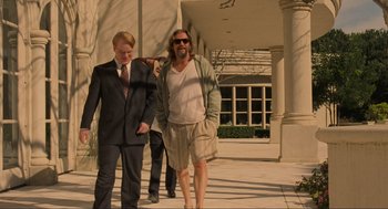 Movie still from “The Big Lebowski” (1998), directed by Ethan Coen – Two men walking down a sidewalk in front of a building; Wide shot, Low angle