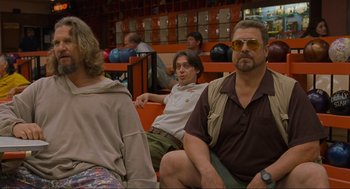 Movie still from “The Big Lebowski” (1998), directed by Ethan Coen – Two men and a woman are sitting on a bench; Medium shot, Low angle
