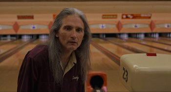 Movie still from “The Big Lebowski” (1998), directed by Ethan Coen – An older man with long grey hair standing in front of a bowling lane; Close Up shot, Low angle