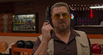 Movie still from “The Big Lebowski” (1998), directed by Ethan Coen – A man with a gun in his hand and sunglasses on; Close Up shot, Low angle