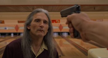 Movie still from “The Big Lebowski” (1998), directed by Ethan Coen – A man holding a gun pointed at another man in a bowling alley; Close Up shot, Low angle