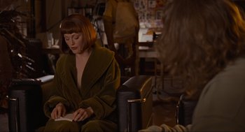 Movie still from “The Big Lebowski” (1998), directed by Ethan Coen – A woman sitting on a chair reading a book; Medium shot, Over the shoulder angle