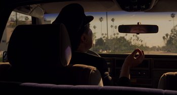 Movie still from “The Big Lebowski” (1998), directed by Ethan Coen – A man sitting in the back seat of a car looking out the window; Medium shot, Over the shoulder angle