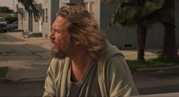 Movie still from “The Big Lebowski” (1998), directed by Ethan Coen – A man with long hair sitting on the ground; Close Up shot, Over the shoulder angle