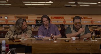 Movie still from “The Big Lebowski” (1998), directed by Ethan Coen – A group of men sitting at a table in front of a bowl; Medium shot, Low angle