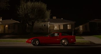 Movie still from “The Big Lebowski” (1998), directed by Ethan Coen – A red sports car parked on the side of the street; Wide shot, High angle