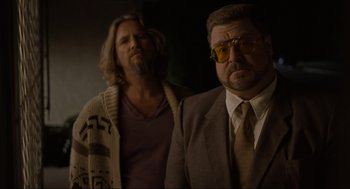 Movie still from “The Big Lebowski” (1998), directed by Ethan Coen – A man in a suit standing next to another man in a suit; Medium shot, Low angle