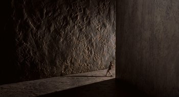 Movie still from “The Big Lebowski” (1998), directed by Ethan Coen – A person walking in front of a stone wall; Extreme Wide shot, High angle