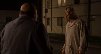 Movie still from “The Big Lebowski” (1998), directed by Ethan Coen – A man with long hair and a beard standing next to another man; Medium shot, Over the shoulder angle
