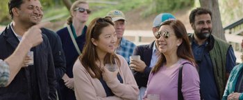 Movie still from “The Biggest Little Farm: The Return” (2022), directed by John Chester – A group of people sitting next to each other holding drinks; Medium shot, High angle