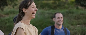 Movie still from “The Biggest Little Farm: The Return” (2022), directed by John Chester – A woman and a man laughing together outside; Medium shot, Over the shoulder angle