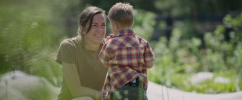 Movie still from “The Biggest Little Farm: The Return” (2022), directed by John Chester – A woman and a boy are smiling for the camera; Medium shot, Over the shoulder angle