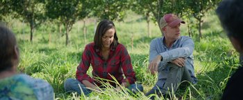 Movie still from “The Biggest Little Farm: The Return” (2022), directed by John Chester – A woman sitting next to a man in the grass; Medium shot, Over the shoulder angle