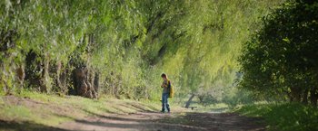 Movie still from “The Biggest Little Farm: The Return” (2022), directed by John Chester – A young boy with a backpack walking down a dirt road; Extreme Wide shot, Low angle