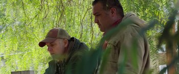 Movie still from “The Biggest Little Farm: The Return” (2022), directed by John Chester – Two men are standing in the woods looking at each other; Medium shot, Low angle