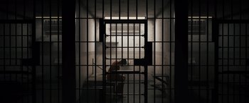 Movie still from “The Binge” (2020), directed by Jeremy Garelick – A man sitting in a jail cell with his head in his hands; Extreme Wide shot, High angle