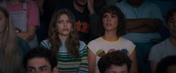 Movie still from “The Binge” (2020), directed by Jeremy Garelick – Two women sitting in front of each other in front of a crowd of onlookers; Close Up shot, High angle