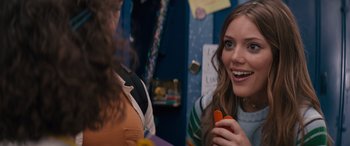 Movie still from “The Binge” (2020), directed by Jeremy Garelick – A woman holding an orange in her hand and smiling; Close Up shot, Over the shoulder angle