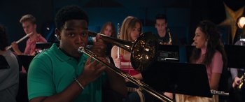 Movie still from “The Binge” (2020), directed by Jeremy Garelick – A group of young people playing instruments in a room; Medium shot, Low angle