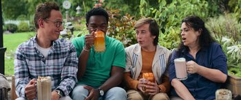 Movie still from “The Binge” (2020), directed by Jeremy Garelick – A group of young men sitting next to each other holding drinks; Medium shot, Over the shoulder angle